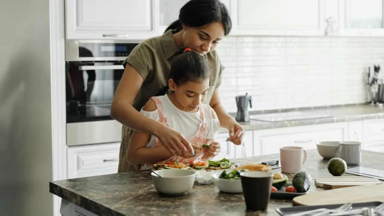 Madre cocinando con su hija. / Pexels.com.
