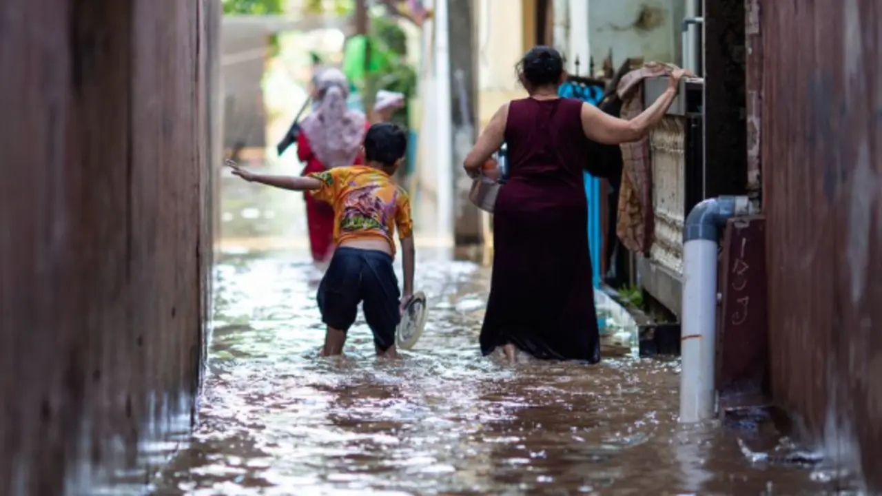 Una mujer y su hijo caminan en un &aacute;rea inundada en el este de Yakarta, Indonesia, en febrero de 2021. / UNICEF