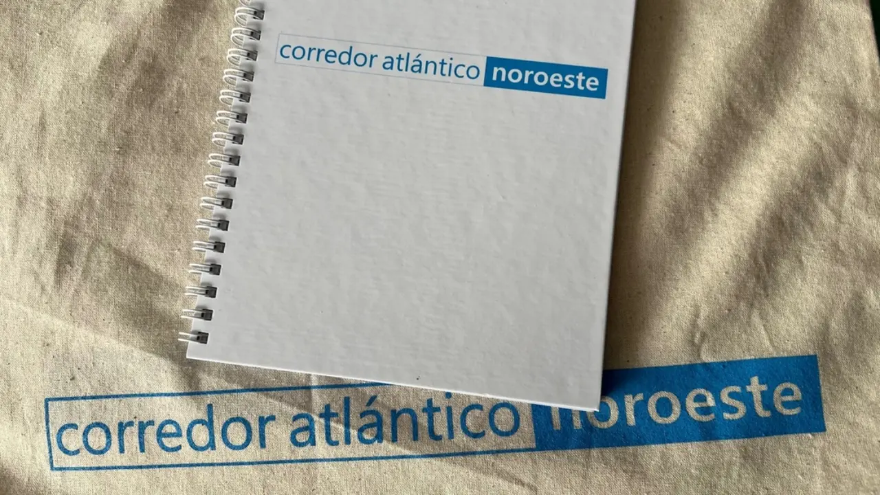 Una libreta y una bolsa rotuladas por el Corredor Atlántico. / Mundiario