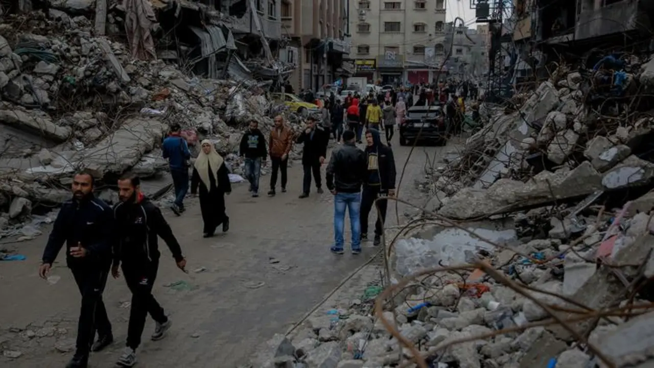 Varias personas pasan junto a sus casas destruidas en el norte de la Franja de Gaza. / UNICEF.
