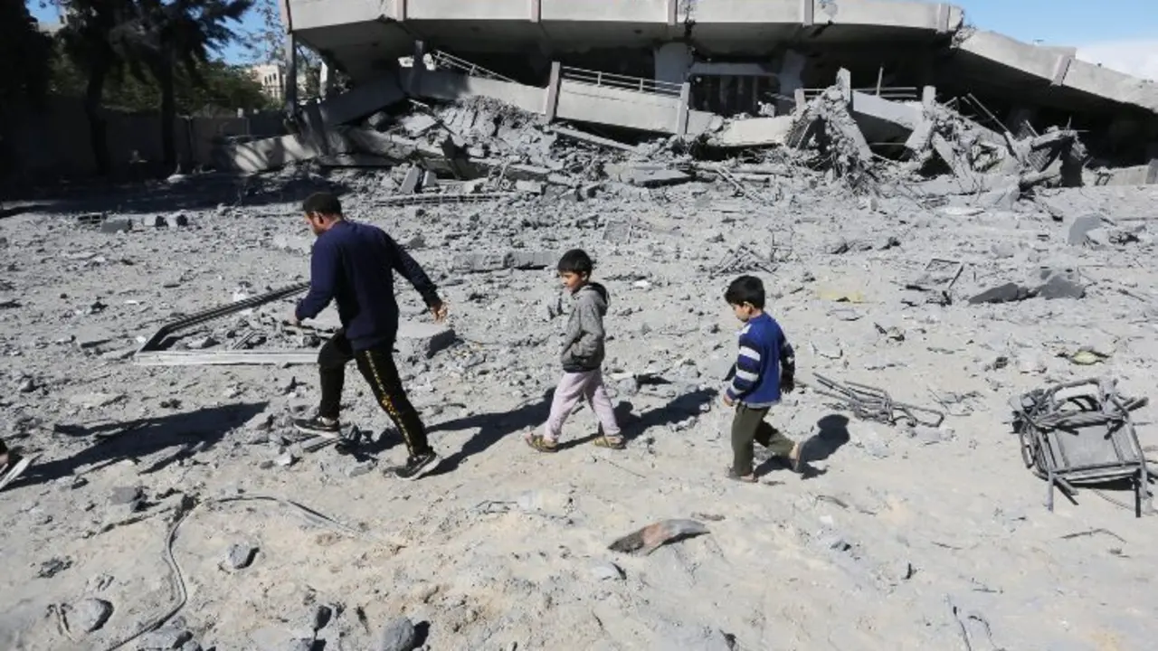 Un hombre y unos ni&ntilde;os caminando por los escombros en Gaza. / @UNRWAes.