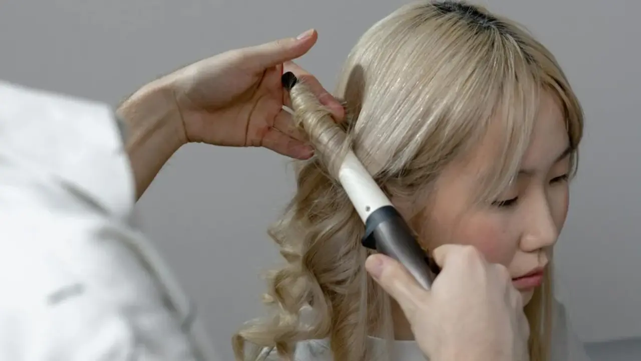 Mujer con tenaza de pelo y rizos.