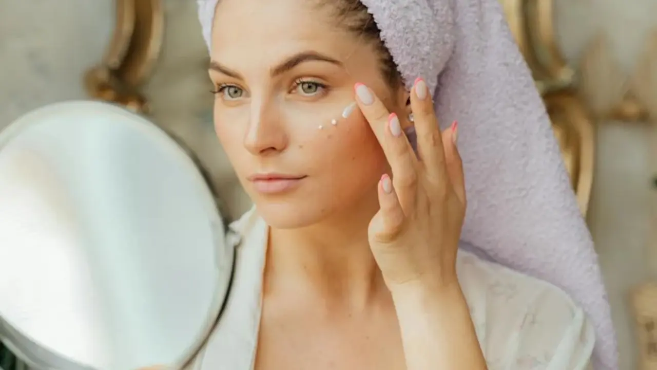 Mujer con crema facial y espejo frontal.