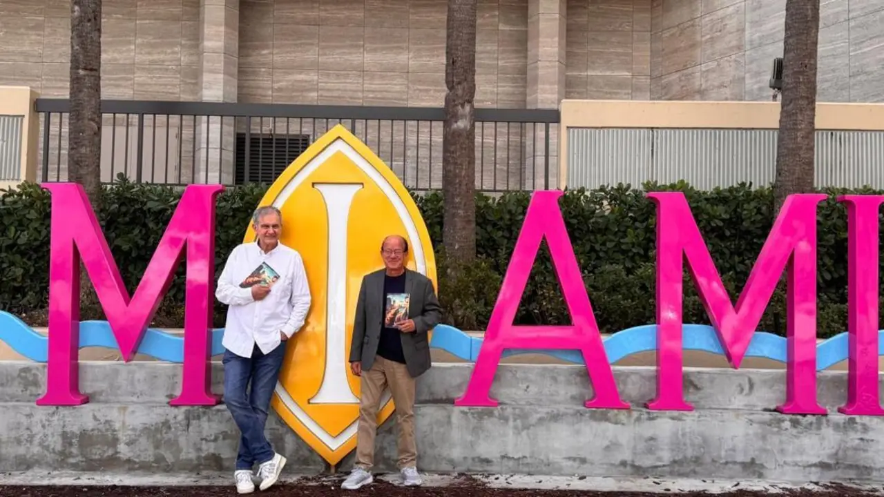 José Luis Gómez, editor de Mundiediciones, y Andrés Hernández Alende, autor de El ocaso, ante un cartel de Miami, en el downtown de la ciudad del sol. / Mundiario