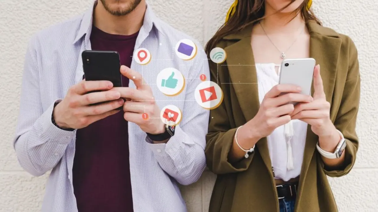Dos j&oacute;venes atendiendo a sus redes sociales en sus tel&eacute;fonos. / PrensaLink.