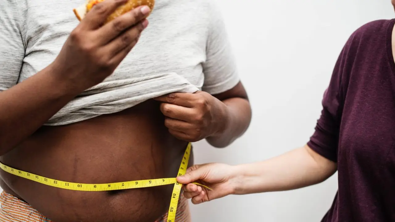 Una mujer mide la barriga de un hombre obeso. / RR SS.
