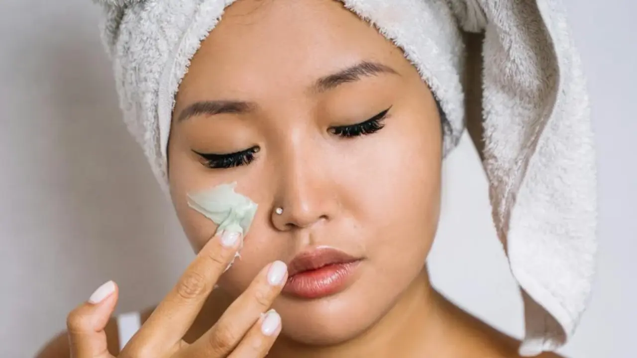 Mujer con crema facial hidratante.