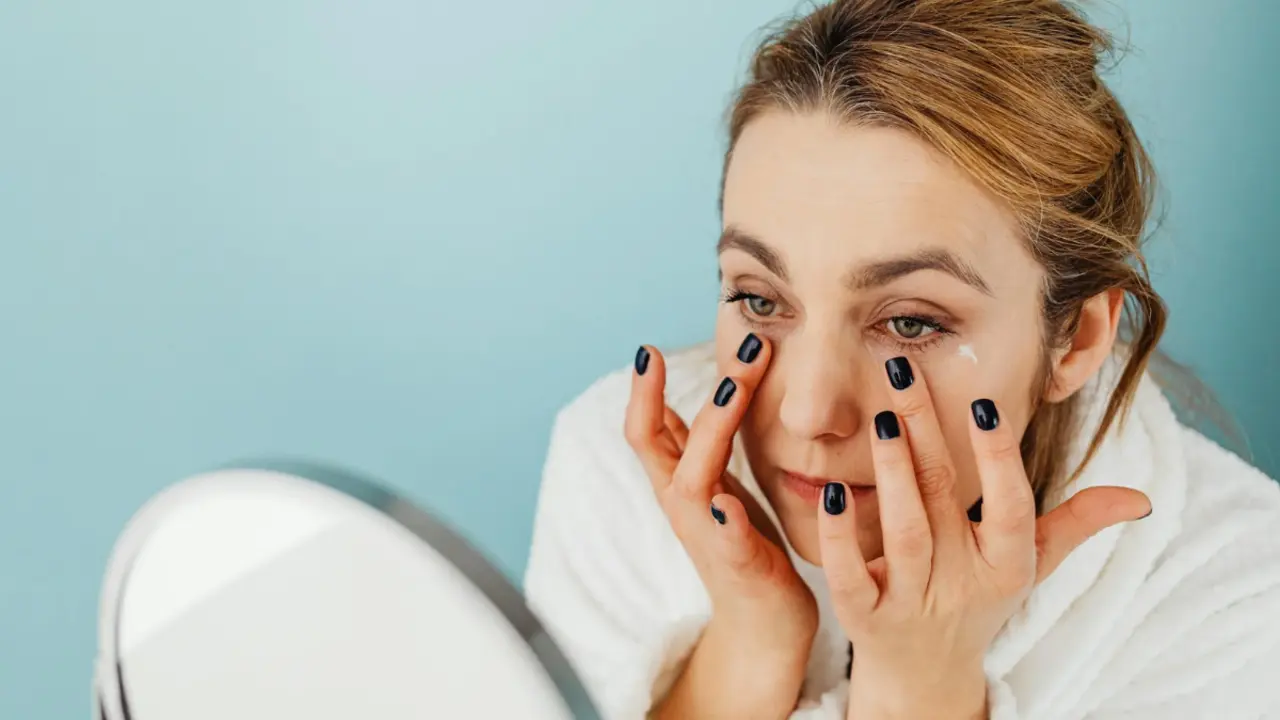 Mujer con contorno de ojos frente a un espejo. 