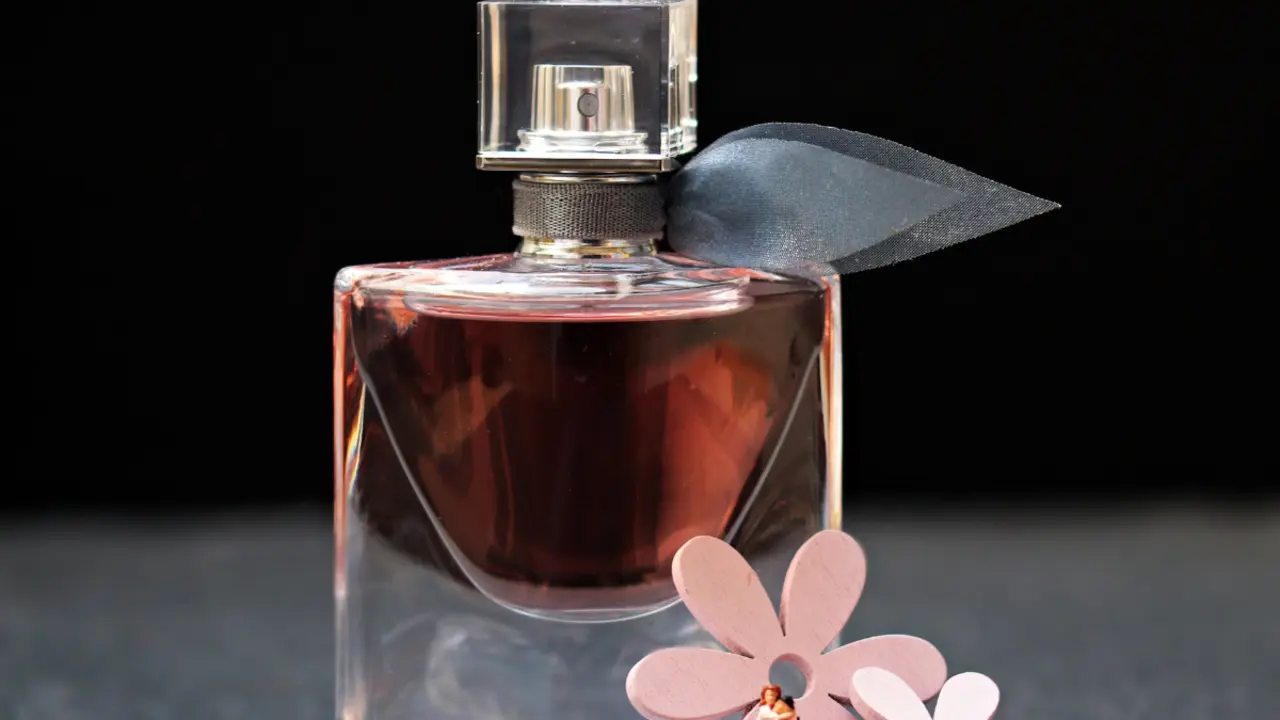 Envase de perfume con flores alrededor.