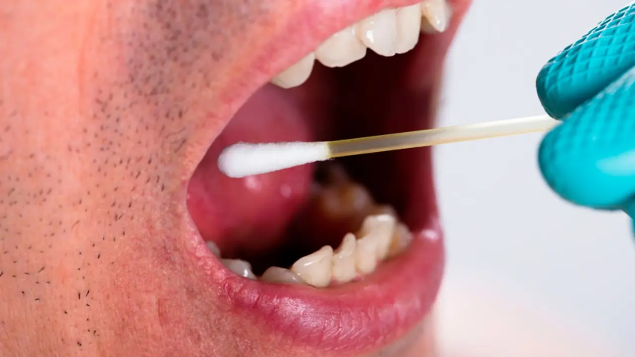 Un hombre se toma una muestra de saliva con un hisopo. / RR. SS.