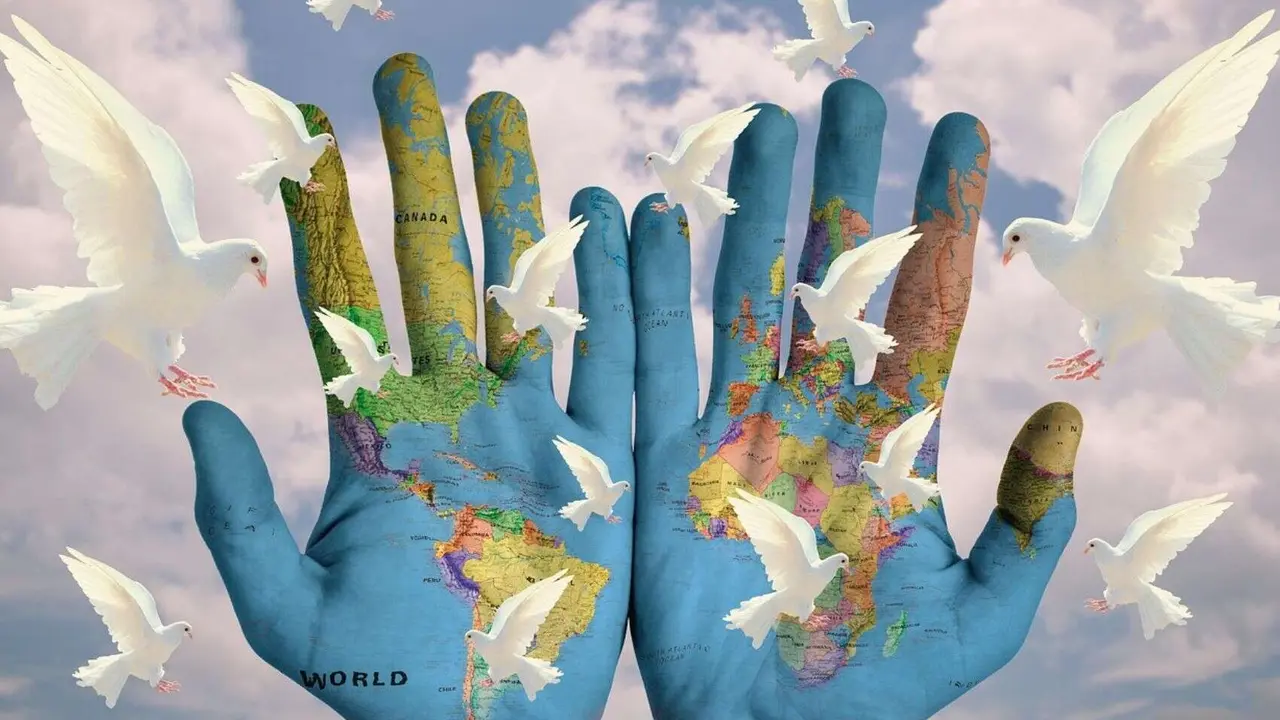 Unas manos con el mapa del mundo y palomas de la paz. / RR SS.