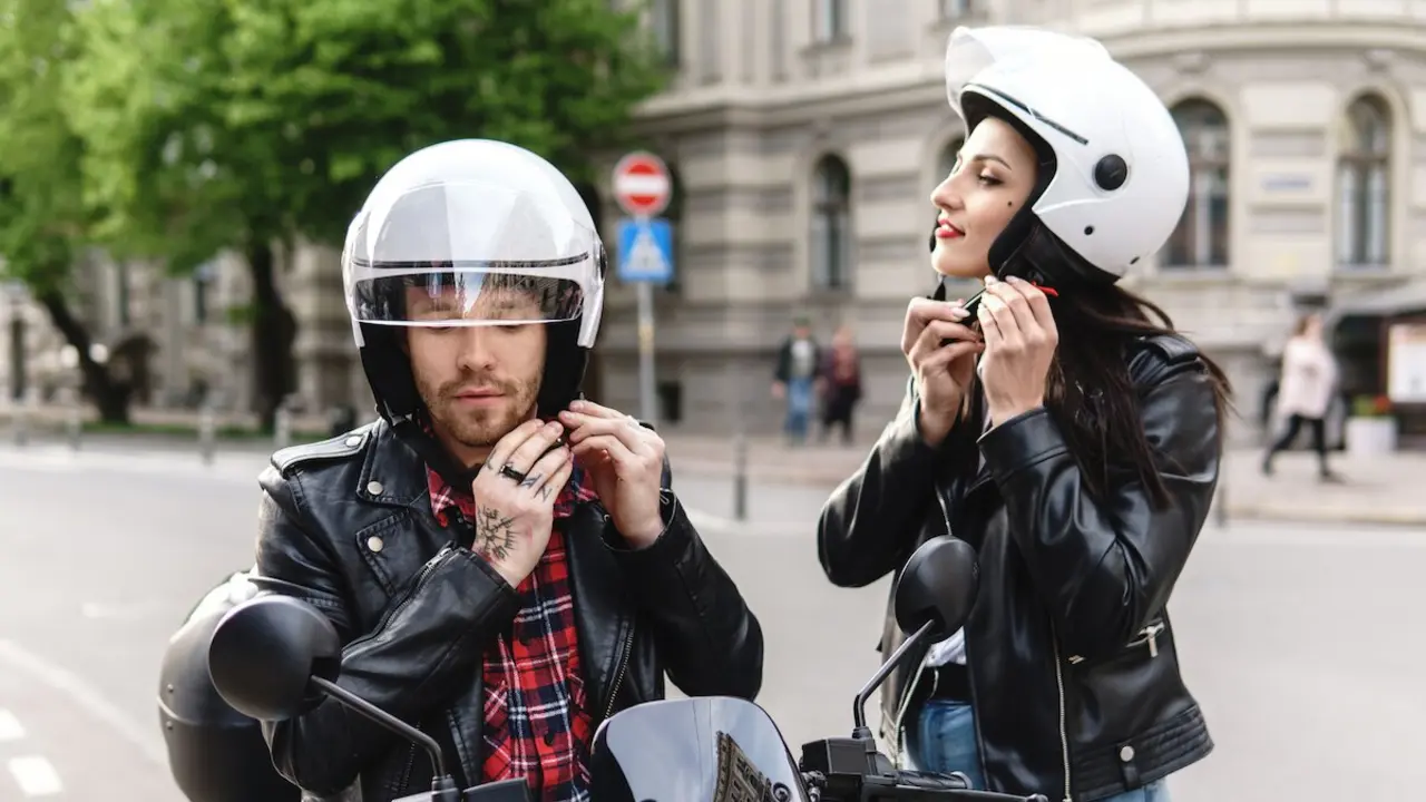 Una pareja poniéndose el casco de la moto.