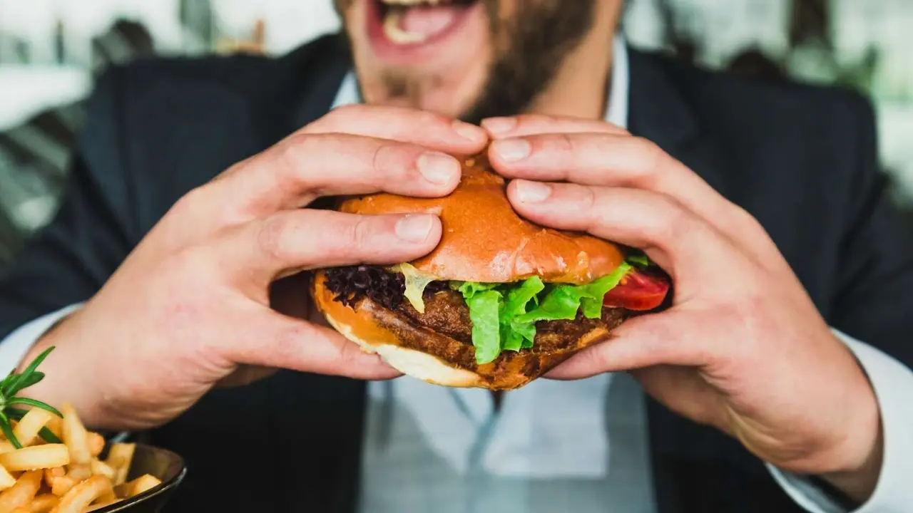 Un hombre come una hamburguesa. / Unsplash.