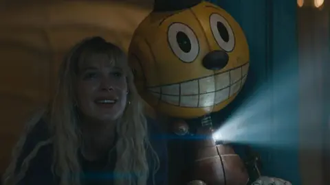 Alan Tudyk y Millie Bobby Brown en Estado el&eacute;ctrico (2025) / IMDb