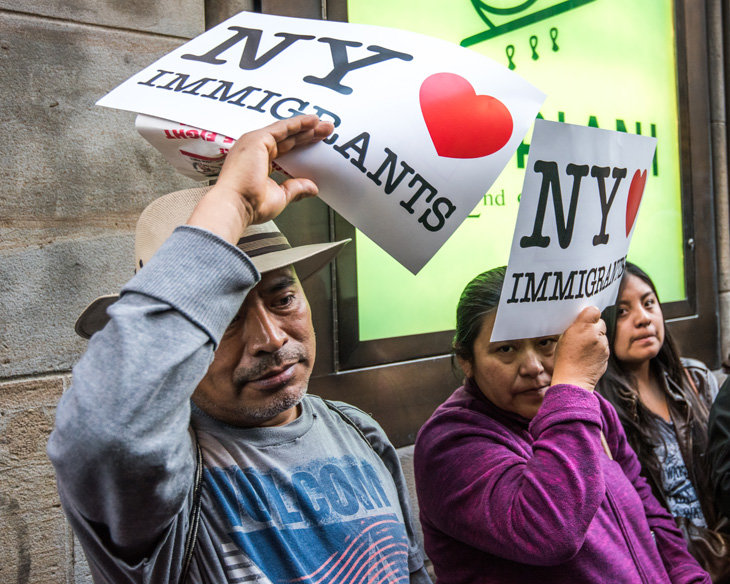 Inmigrantes latinos con carteles que rezan 